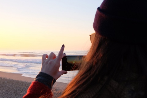 Chica haciendo una fotografía durante una puesta de sol