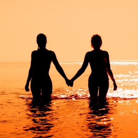 Pareja entrando en el mar durante el atardecer