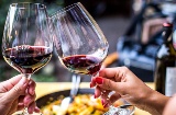 Un toast avec un verre de vin rouge et une paella en arrière-plan