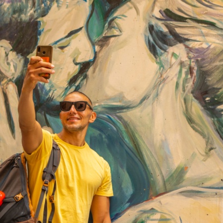 Турист делает селфи на фоне одного из изображений граффити в Валенсии, Валенсийское сообщество
