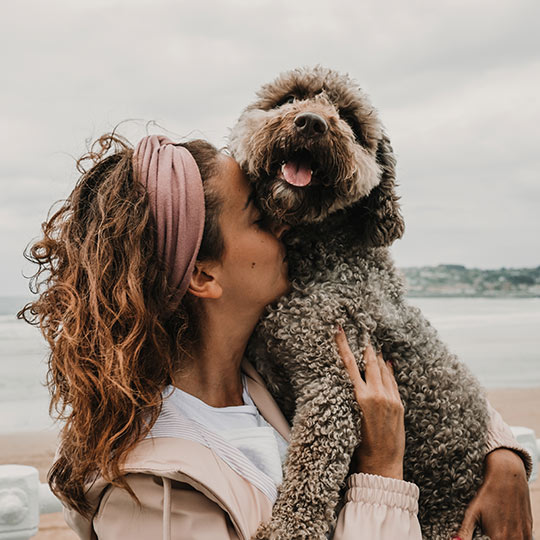 Turista abrazando a su mascota en la playa de Gijón, Asturias