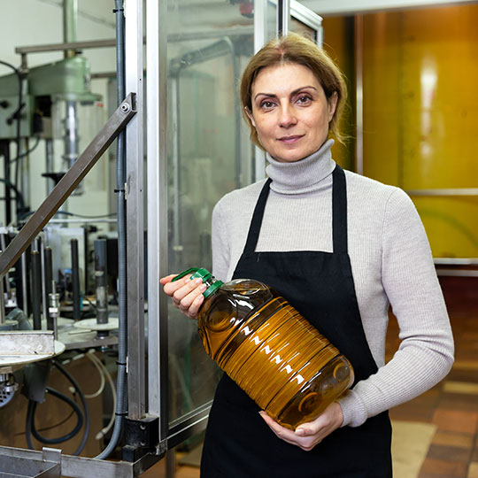 オリーブオイル工場で瓶を見せる女性