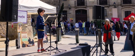 Kind liest Don Quijote vor der Kathedrale von Barcelona an Sant Jordi