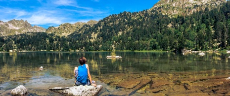 Sitzendes Kind an einem der Seen des Nationalparks Aigüestortes i Estany de Sant Maurici in Lérida, Katalonien