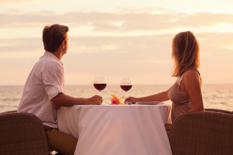 Casal compartilhando uma taça de vinho em frente ao mar