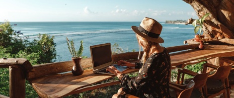Une femme travaillant sur son ordinateur face à la mer